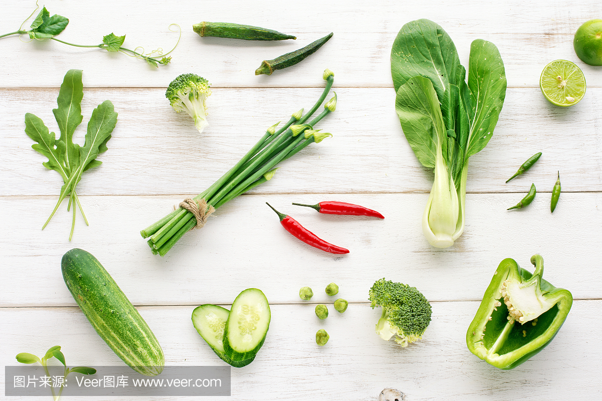木制餐桌上的绿色有机蔬菜搭配红辣椒。俯视图